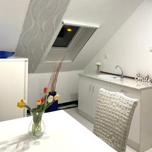 a white kitchen with a vase of flowers on a table at Zajer Apartment Ház in Hajdúszoboszló +52 photos