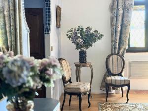 a room with two chairs and a vase with flowers at Le Manoir médiéval de Garance in Châteaumur