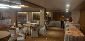 a room with tables and chairs and a man standing in a room at Harrisons Hotel in Chennai