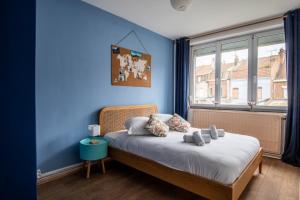 une chambre avec un lit avec un mur bleu dans l'établissement Family Home in Lille, Garden and Parking - 6/8p, à Lille