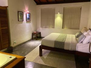 a bedroom with a bed and a bathroom with a sink at Tibline by Gotravelfix in Kudadeniya +39 photos