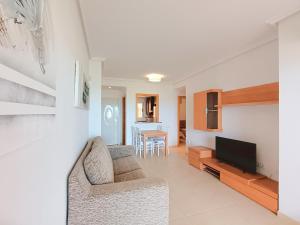 Una sala de estar con un sofá y un televisor. en Ayf vistas de lujo en 1ª linea de playa, en El Borseral