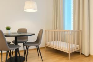 una culla in una stanza con tavolo e sedie di Tammer Huoneistot - City Suite 3 - Public Sauna, Gym & Pool a Tampere Altre 10 foto
