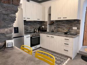 a kitchen with white cabinets and yellow chairs at Katoi Apartment in Loutrá