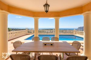 stół na balkonie z widokiem na basen w obiekcie Villa Gran Sol by Abahana Villas w mieście Calpe