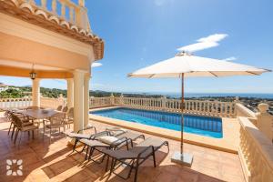 patio ze stołami, parasolem i basenem w obiekcie Villa Gran Sol by Abahana Villas w mieście Calpe