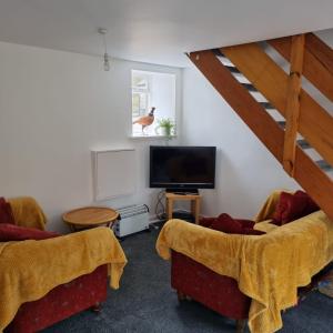 a living room with two couches and a flat screen tv at Killean Farmhouse Cottages in Auchnangoul