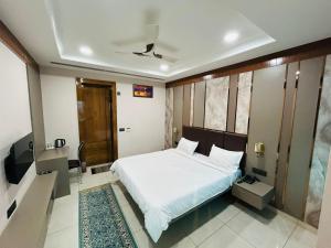 a bedroom with a white bed and a tv at JMD Hotel in Farrukhnagar
