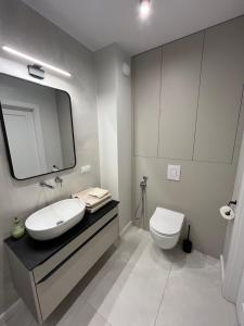 グダニスクにあるSeaLake Apartments - Gdańsk Letnicaの洗面台、トイレ、鏡のあるバスルーム +10枚の写真