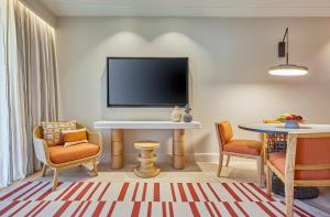 a living room with a tv and a table and chairs at The Westin Resort, Costa Navarino in Romanu