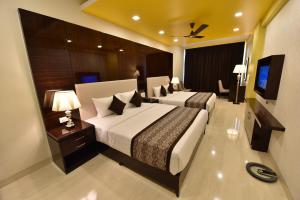 a hotel room with two beds and a flat screen tv at Hotel Calangute Central in Calangute