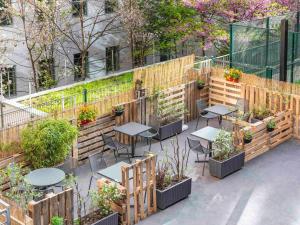 a patio with tables and chairs in a garden at ibis budget Paris Porte de Vincennes in Paris