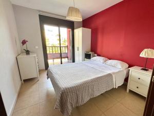 Un dormitorio con una pared roja y una cama. en Apartamento de lujo en Residencial El Mocan, en Palm-mar 18 fotos más