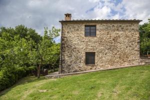 un edificio de piedra con un campo de hierba delante de él en Agriturismo Podere Il Colle, en Radicondoli