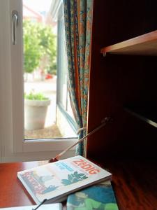 a book sitting on a table next to a window at La Belle Aventure in Pont-lʼÉvêque