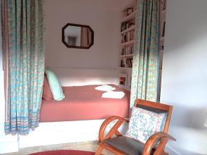 a bedroom with a bed with a chair and a mirror at La Belle Aventure in Pont-lʼÉvêque