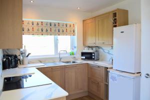 a kitchen with wooden cabinets and a white refrigerator at Carreg Coetan Cottage Newport, Pembrokeshire in Newport Pembrokeshire