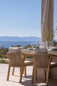 a wooden table with two chairs and wine glasses at Villa Dafni Tinos in Agios Fokas