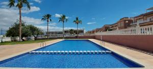 una piscina al lado de un edificio con palmeras en Chalet Adosado en Gran Alacant - Monte y Mar, en Santa Pola