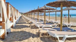 una fila de sombrillas y sillas en una playa en Chalet Adosado en Gran Alacant - Monte y Mar, en Santa Pola