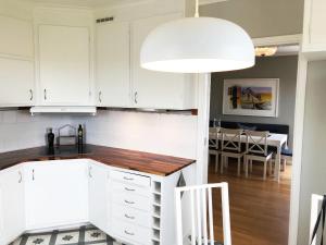 a kitchen with white cabinets and a dining room at West coast villa with stunning ocean view ! in Hovenäset