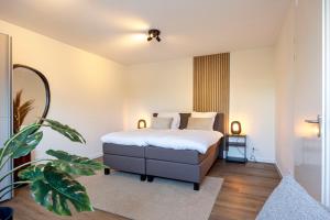 a bedroom with a bed with white sheets and a plant at Harderwold Villa Resort XL in Zeewolde