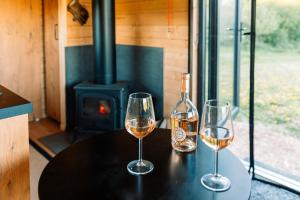 two glasses of wine on a table with a fireplace at Romantic Offgrid Tiny Home Ft Beachy Head Hike in Chiddingly