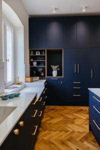 a kitchen with navy blue cabinets and wooden floors at Peacock Apartments Split in Split