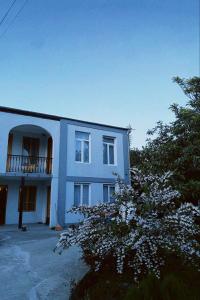 Un edificio blanco con un balcón y un árbol. en Kisa, en Martvili