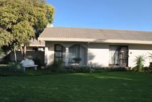 a house with a person sitting on a bench in the yard at Amaris Guesthouse in Lichtenburg