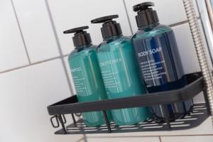 three bottles of detergent sitting on a shelf in a bathroom at Harts Loft - On Beach - Panoramic Sea Views - By Harbour in St Ives +33 photos