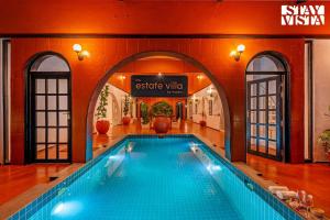 a large swimming pool in a building with a sign at The Estate Villa Where Luxury Meets Serenity in Suntikoppa