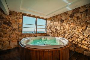 a large bath tub in a room with a stone wall at Hotel Laghetto Bento in Bento Gonçalves