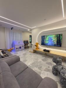 a living room with a couch and a flat screen tv at LYL Ipoh Garden Private Pool Villa-18pax 5BR in Ipoh +42 photos