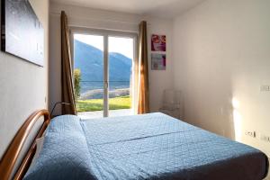 a bedroom with a blue bed and a window at DolceVita Apartment-your vacation on lakes in Carlazzo
