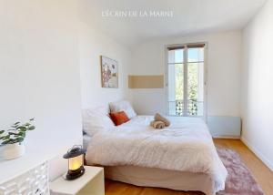a white bedroom with a bed and a window at Appartement 3 pièces proche Paris & Disney in Nogent-sur-Marne