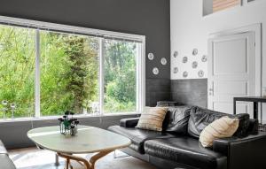 a living room with a black leather couch and a table at 4 Bedroom Cozy Home In Rødby in Kramnitse