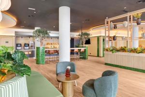 un vestíbulo con plantas, sillas y una mesa en B&B HOTEL Murcia, en Murcia