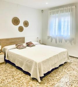 a bedroom with a large white bed and a window at Acogedora casa familiar de 4 habitaciones y gran terraza a metros de la playa in Puerto de Sagunto