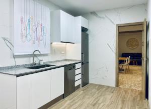 a kitchen with white cabinets and a sink at Acogedora casa familiar de 4 habitaciones y gran terraza a metros de la playa in Puerto de Sagunto