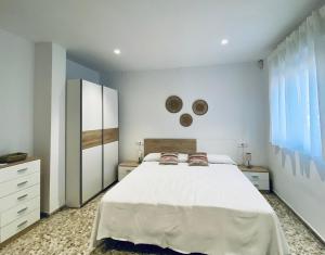 a bedroom with a large white bed with two pillows at Acogedora casa familiar de 4 habitaciones y gran terraza a metros de la playa in Puerto de Sagunto