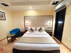 a hotel room with a large bed and a blue chair at The Oakland plaza - Nehru Place by Orion Hotels in New Delhi
