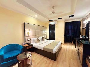 a hotel room with a bed and a blue chair at The Oakland plaza - Nehru Place by Orion Hotels in New Delhi