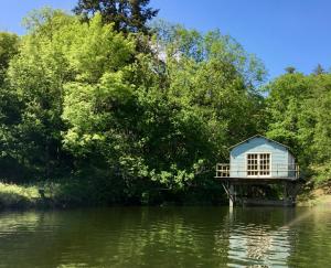 a small blue house on the edge of a body of water at La Frouardière, 3 gîtes de charme in Antigny