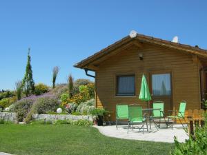 ein Haus mit Stühlen, einem Tisch und einem grünen Sonnenschirm in der Unterkunft Ferienwohnung Spachtholz in Waldmünchen