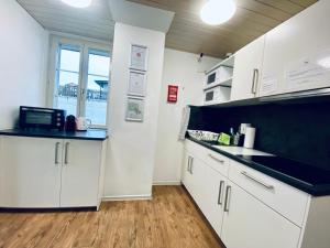 a kitchen with white cabinets and black counter tops at Monteurzimmer - Worker's accommodation - ZIMMERzuVERMIETEN in Biberist in Biberist