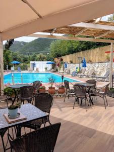 a patio with tables and chairs and a swimming pool at Harmony resort in Parga