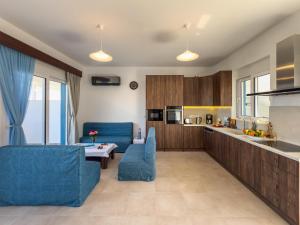 a living room with blue chairs and a kitchen at Laftiras Sea View Home in Archangelos