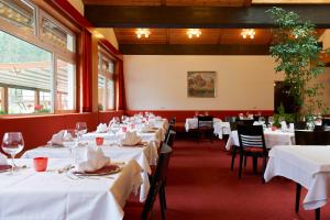 a row of tables in a restaurant with white linens at Hotel Dolomitenhof & Chalet Alte Post in Sesto