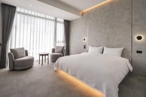 a bedroom with a large white bed and two chairs at KK Villa in Dongshan
